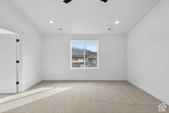 Empty room with light carpet, a ceiling fan, a mountain view, and recessed lighting