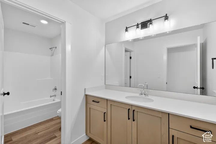 Bathroom featuring vanity,  shower combination, light wood-type flooring, and recessed lighting