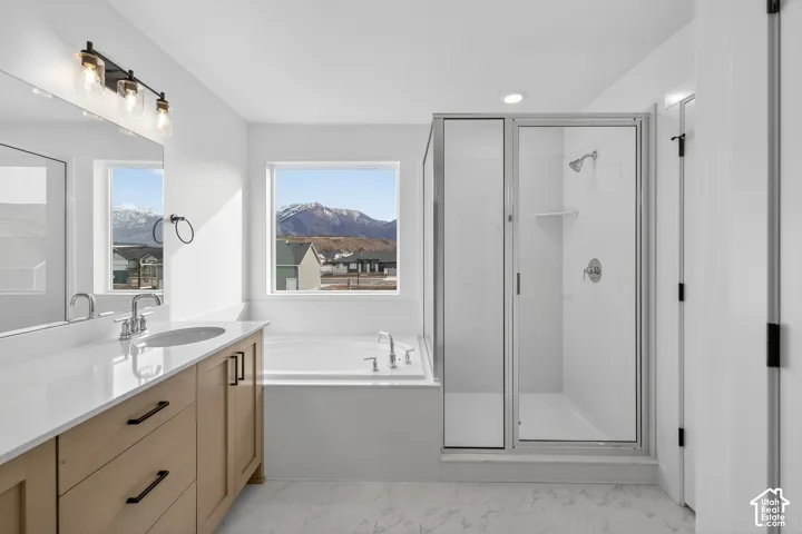 Full bathroom with a shower stall, vanity, a garden tub, a mountain view, and light marble finish flooring