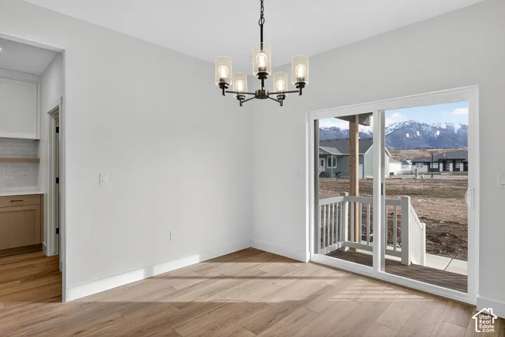 Unfurnished dining area featuring a chandelier, light wood-type flooring, and a mountain view