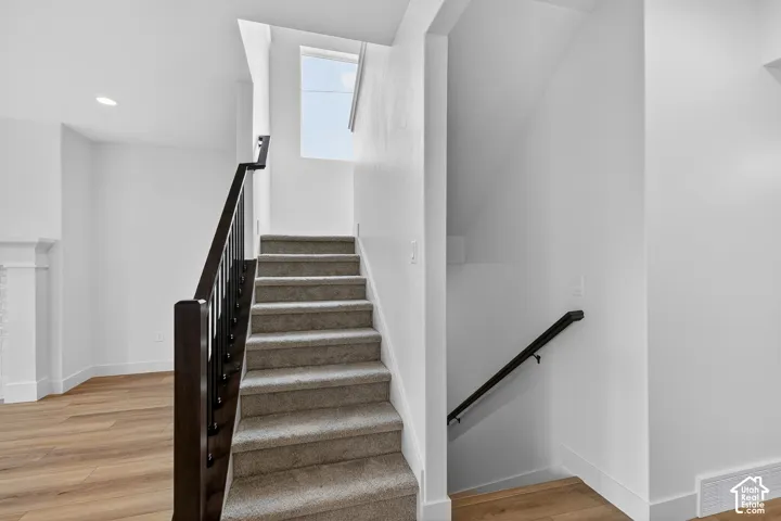 Staircase featuring wood finished floors and recessed lighting