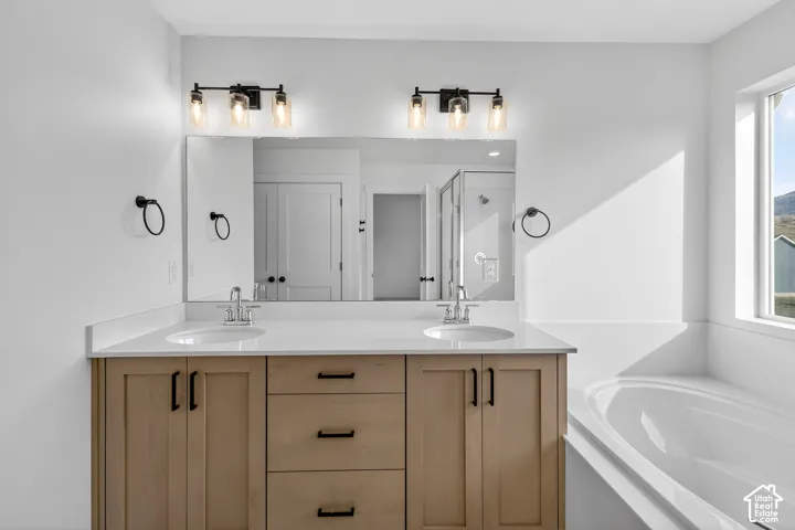 Bathroom with double vanity, a garden tub, and a shower stall