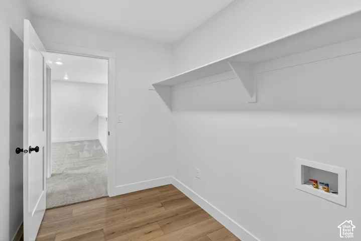 Laundry area with hookup for a washing machine and light wood finished floors