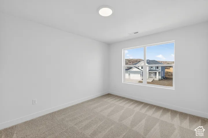 Carpeted spare room with baseboards