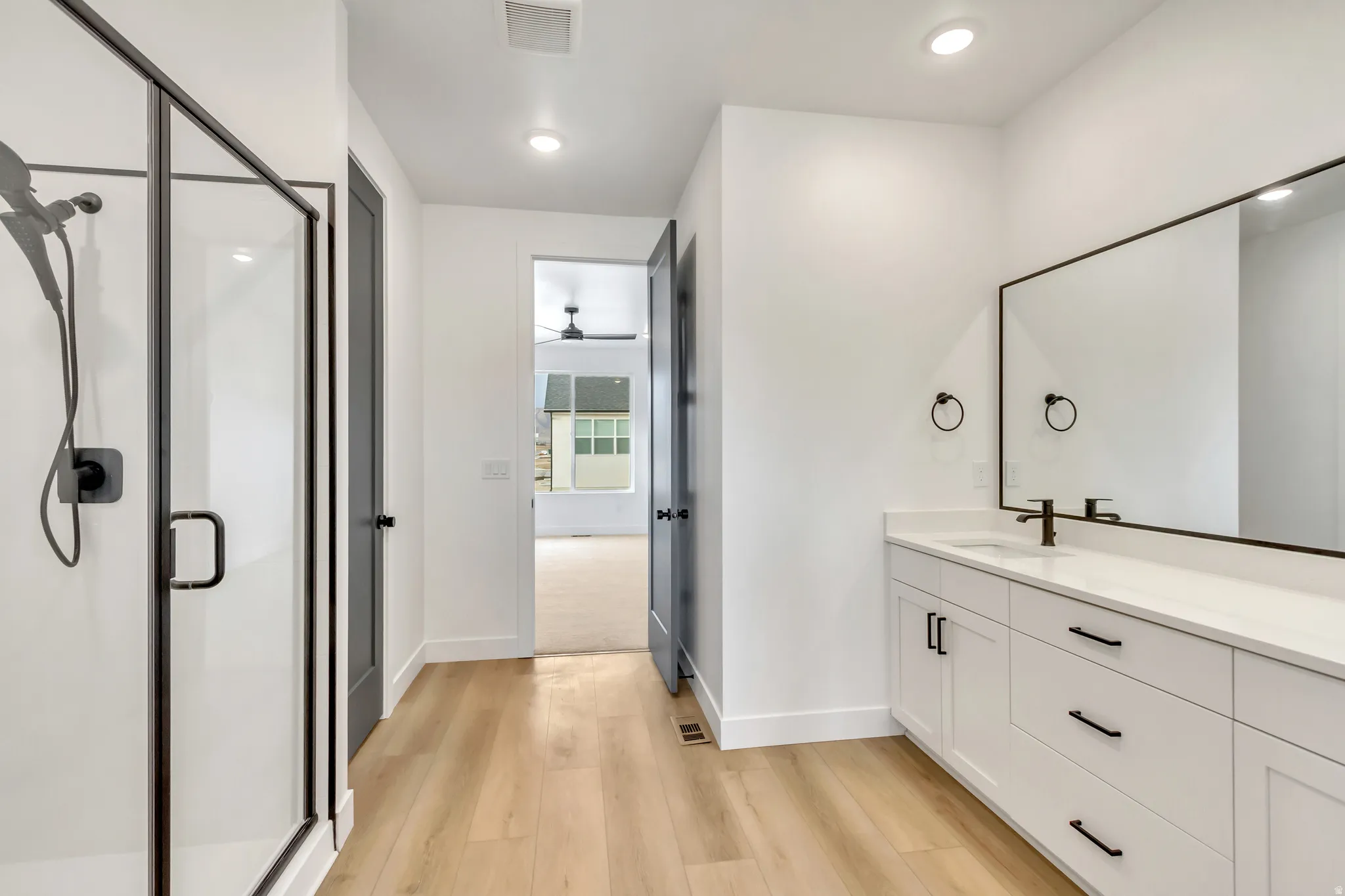 Full bath featuring a shower stall, vanity, light wood-style floors, and recessed lighting