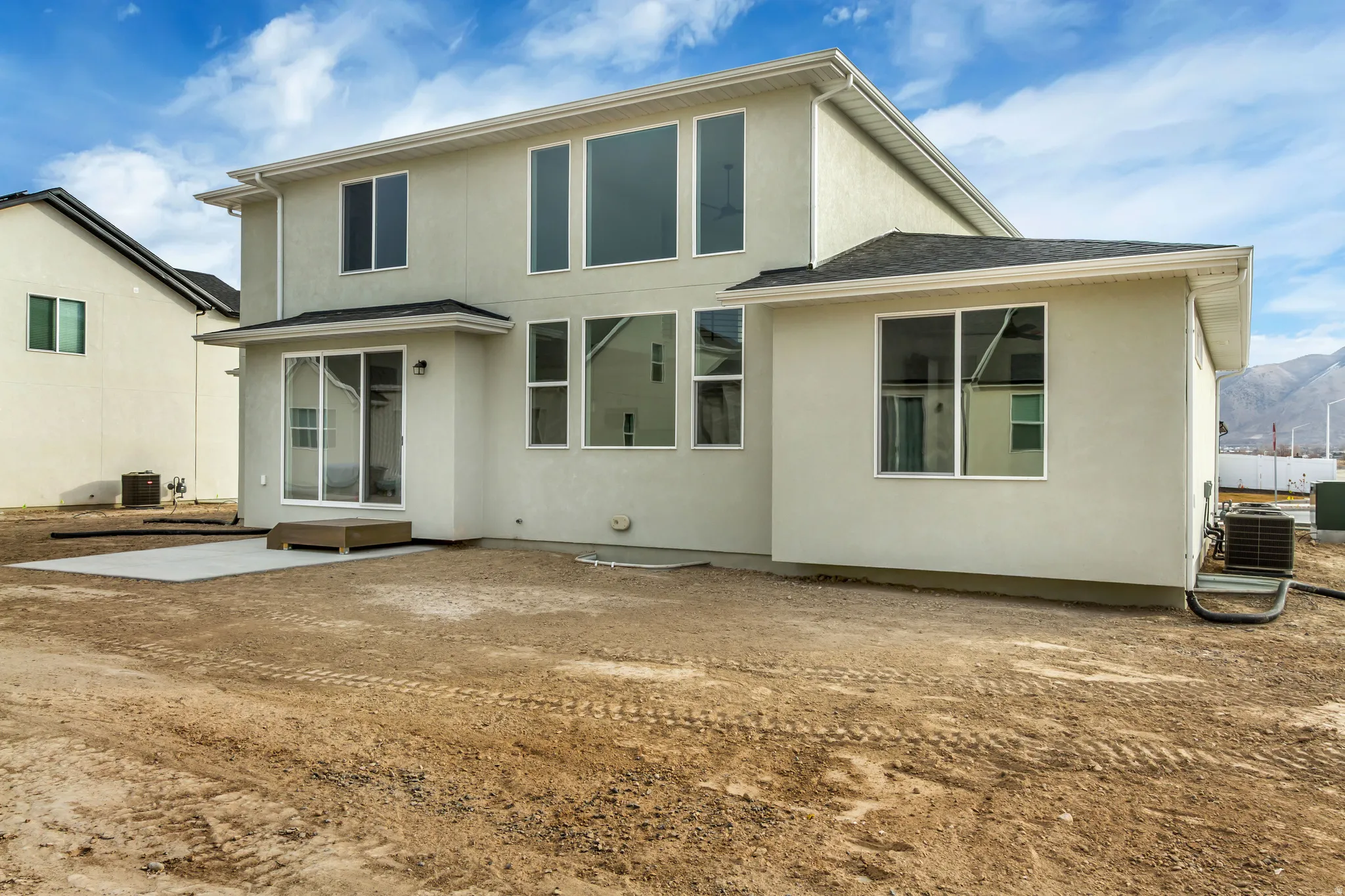 Back of property featuring stucco siding, a patio area, a shingled roof, and a mountain view