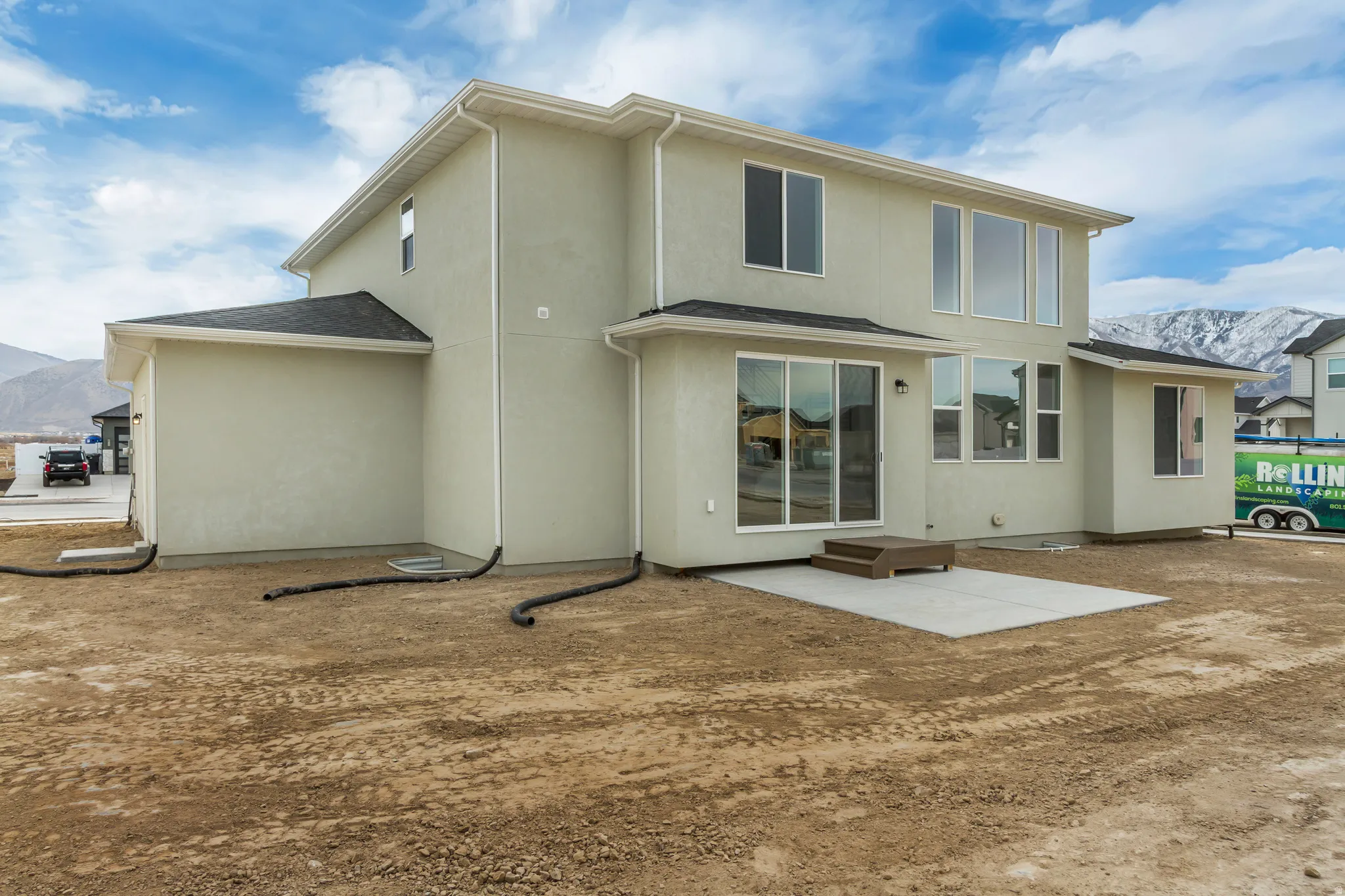 Rear view of property featuring a mountain view, stucco siding, a patio area, and roof with shingles