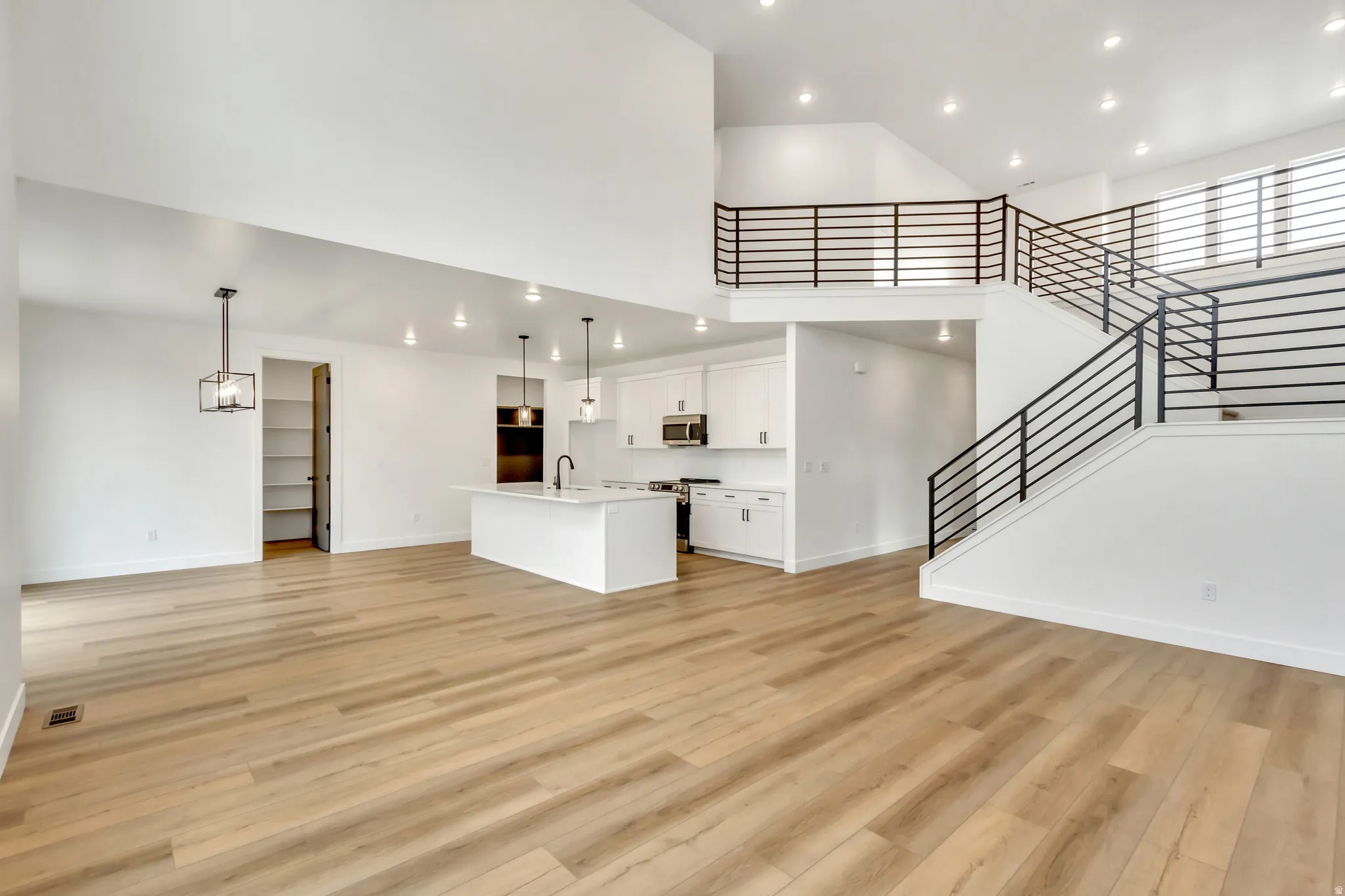 Unfurnished living room with recessed lighting, light wood finished floors, and a high ceiling