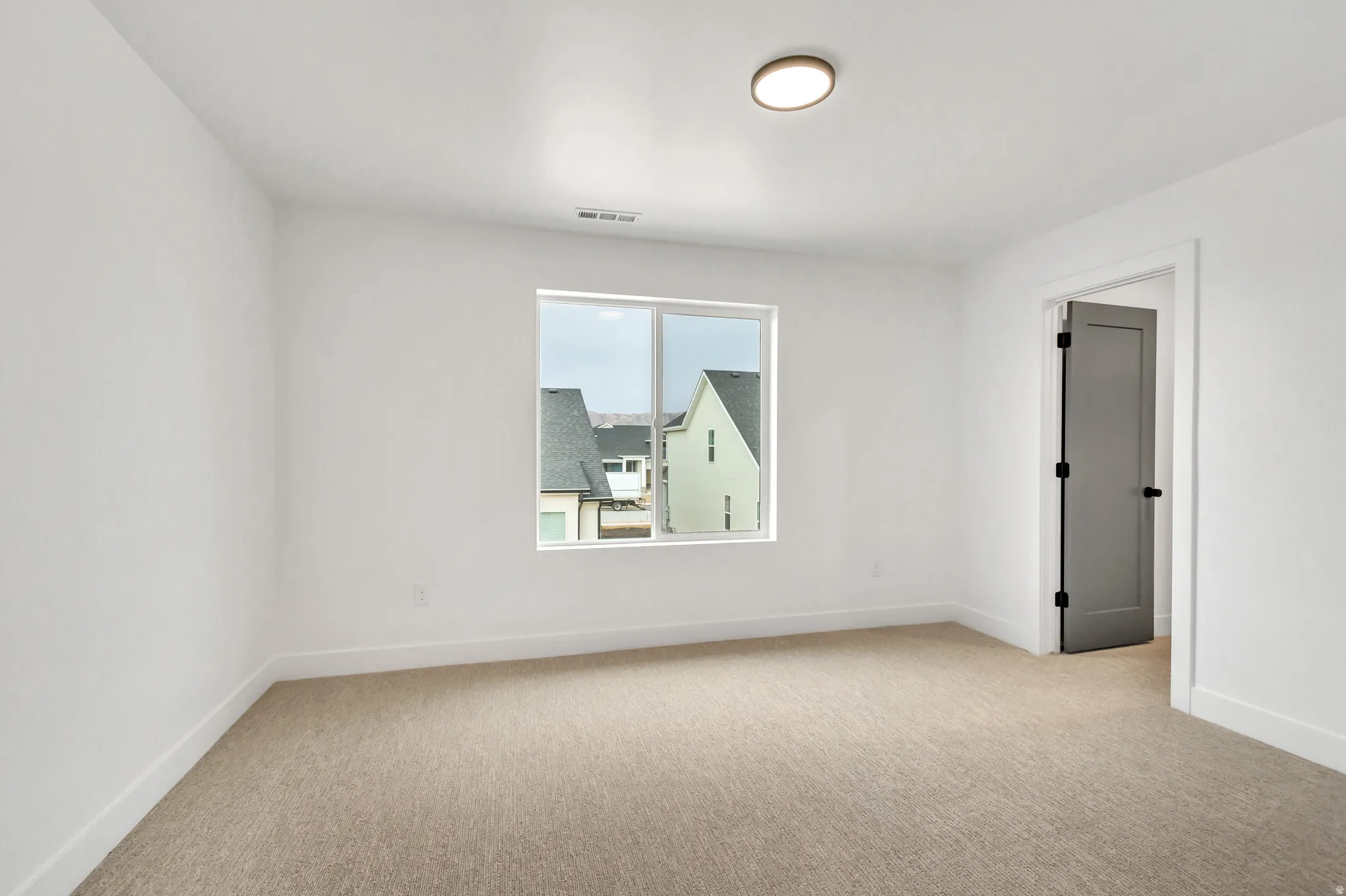 Empty room featuring light colored carpet and baseboards