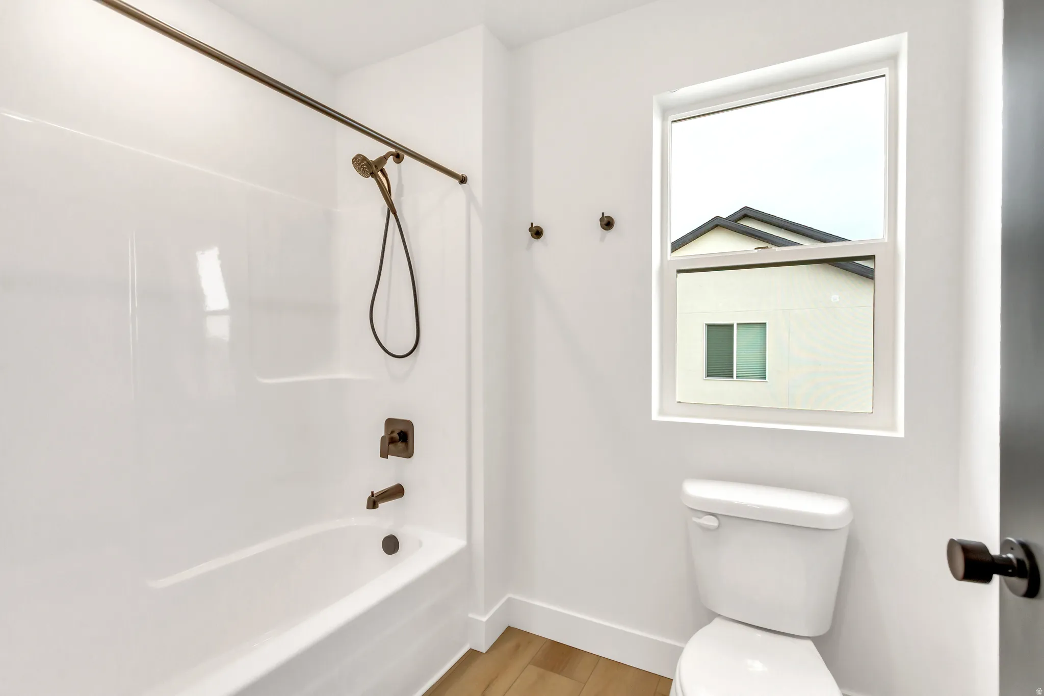 Bathroom with tub / shower combination and light wood finished floors