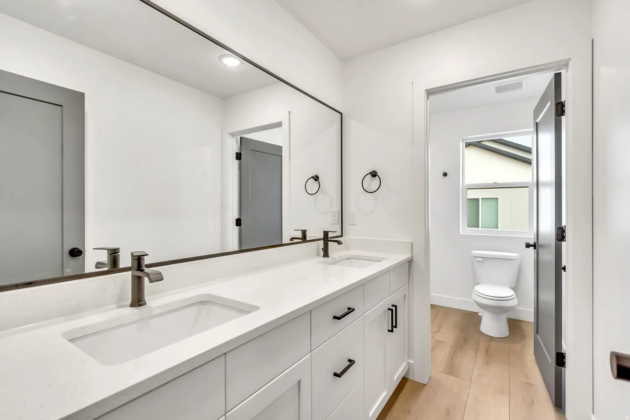 Bathroom with double vanity, light wood-style flooring, and recessed lighting