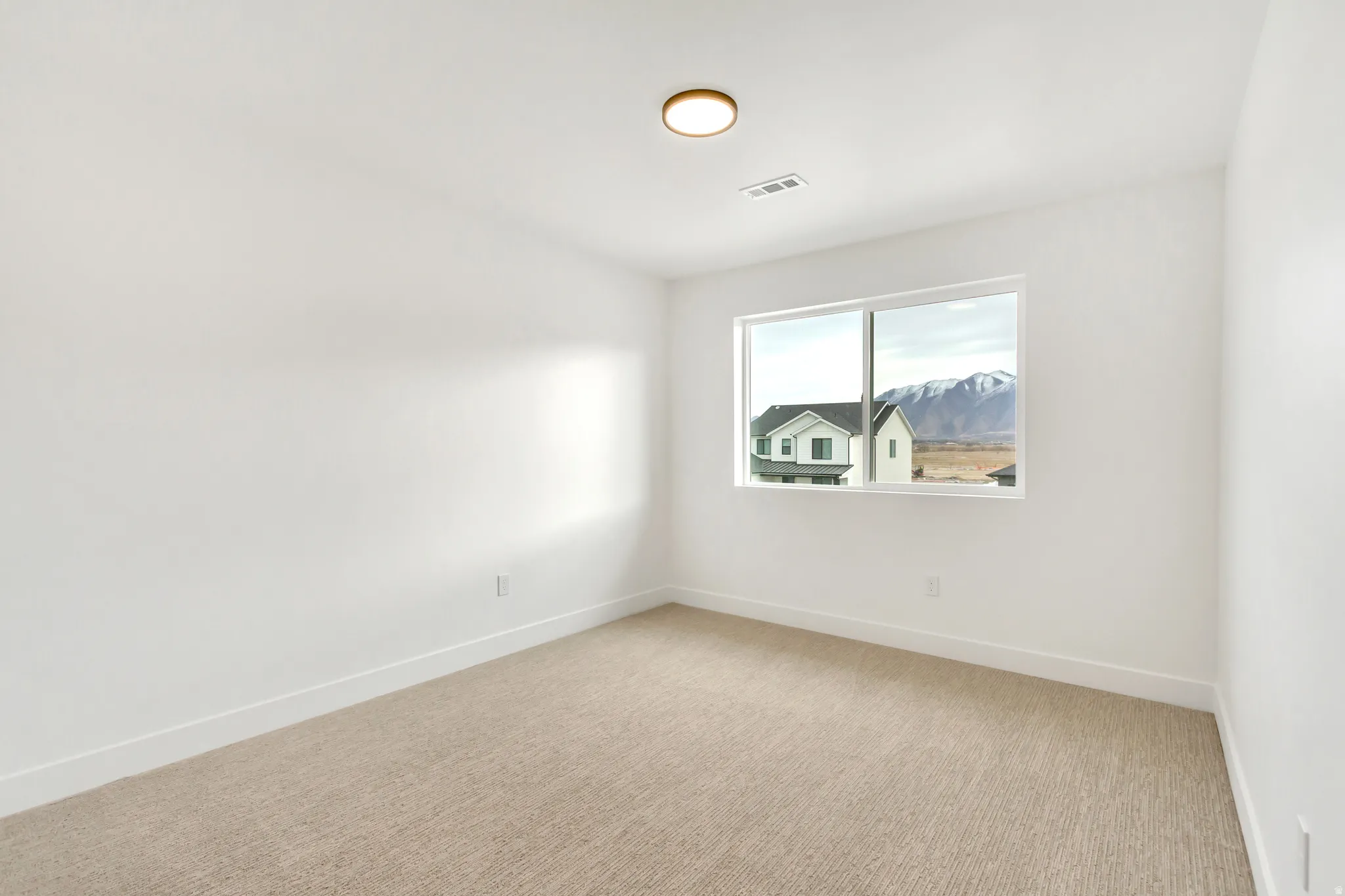 Spare room with light colored carpet and baseboards