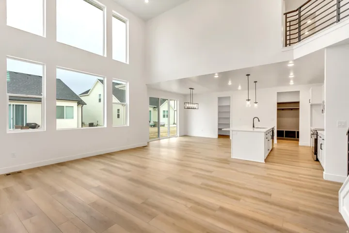 Unfurnished living room featuring recessed lighting, light wood-style flooring, and a high ceiling