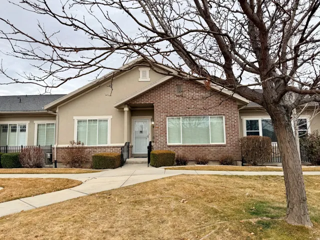 View of front of home with brick siding, stucco siding, and a front lawn