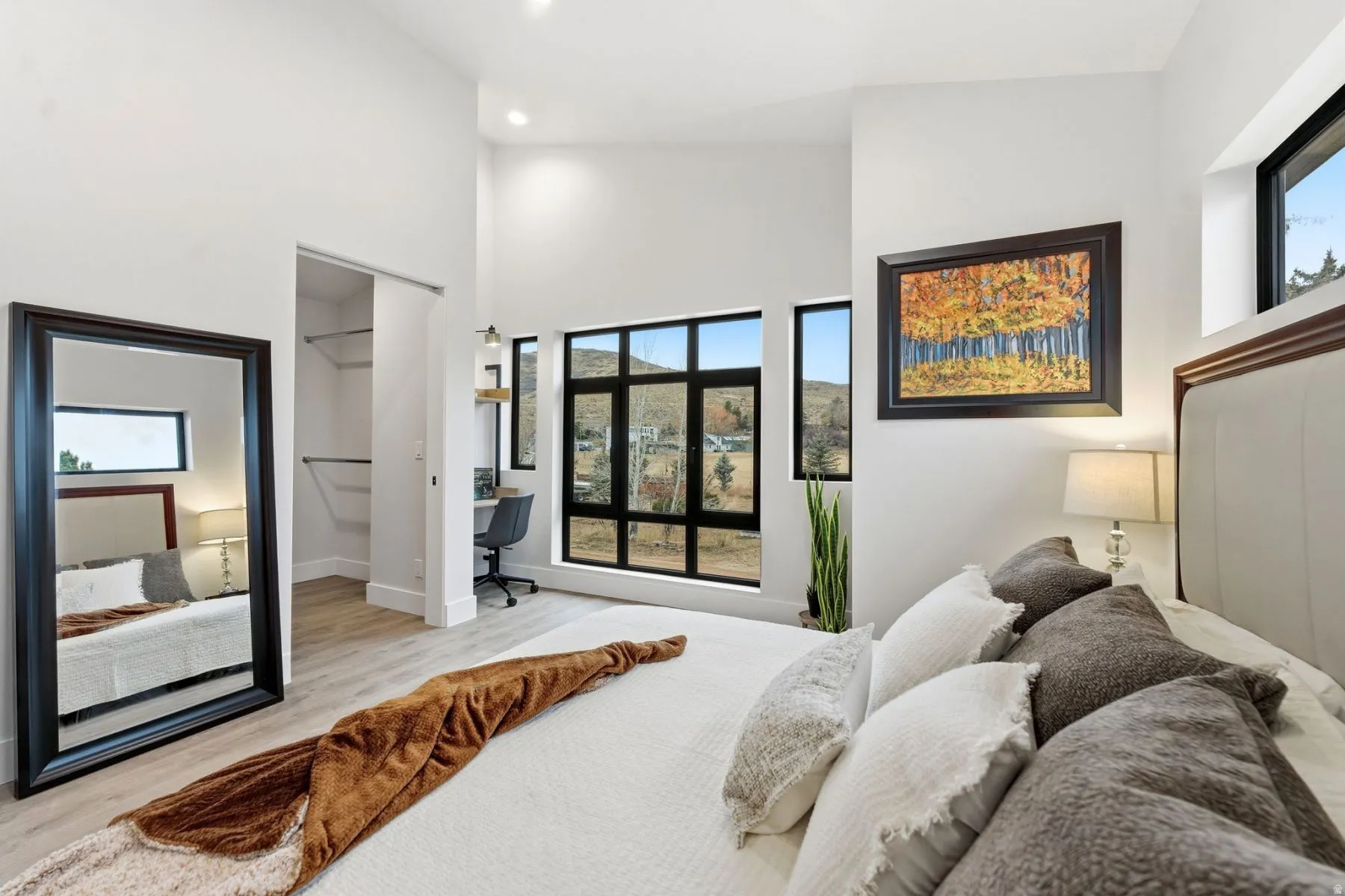 Bedroom with a spacious closet, a high ceiling, an office area, wood finished floors, and recessed lighting