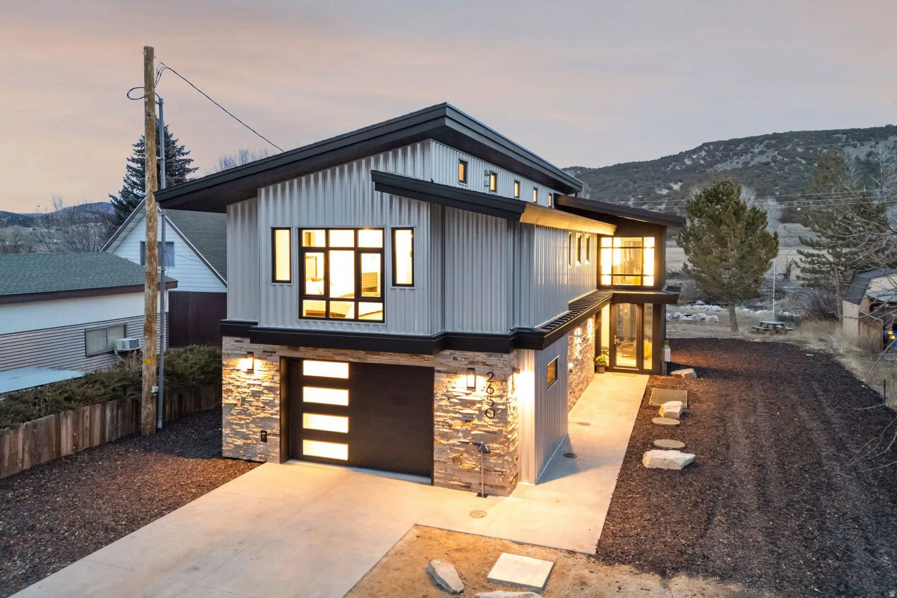 View of front of home with stone siding, a garage, concrete driveway, and board and batten siding