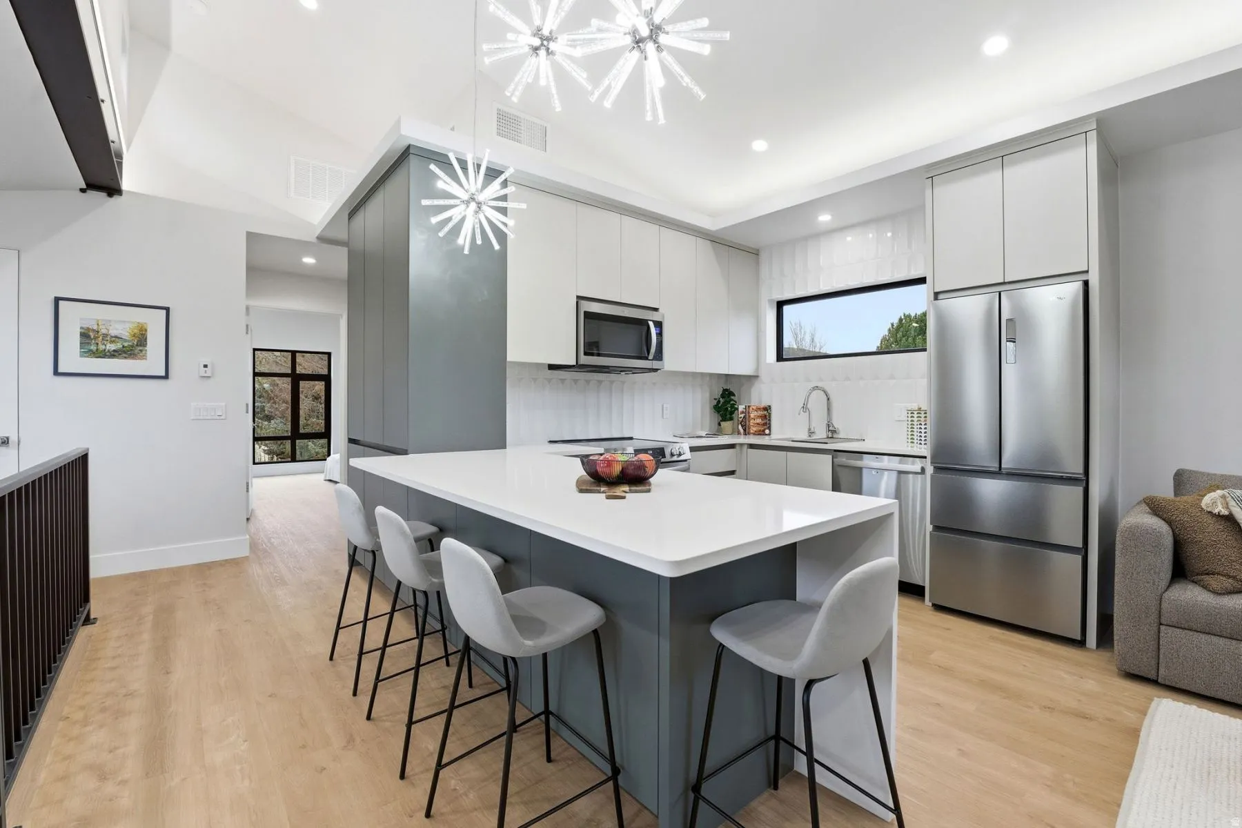 Dual tone kitchen featuring stainless steel appliances, modern cabinets, a kitchen bar, light wood-style flooring, and two tone cabinets