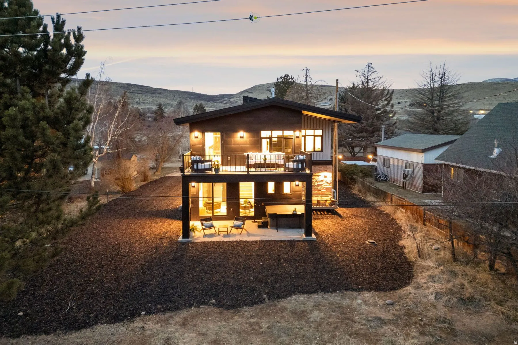 Back of property at dusk featuring a patio, a mountain view, an outdoor lounge area, and a balcony
