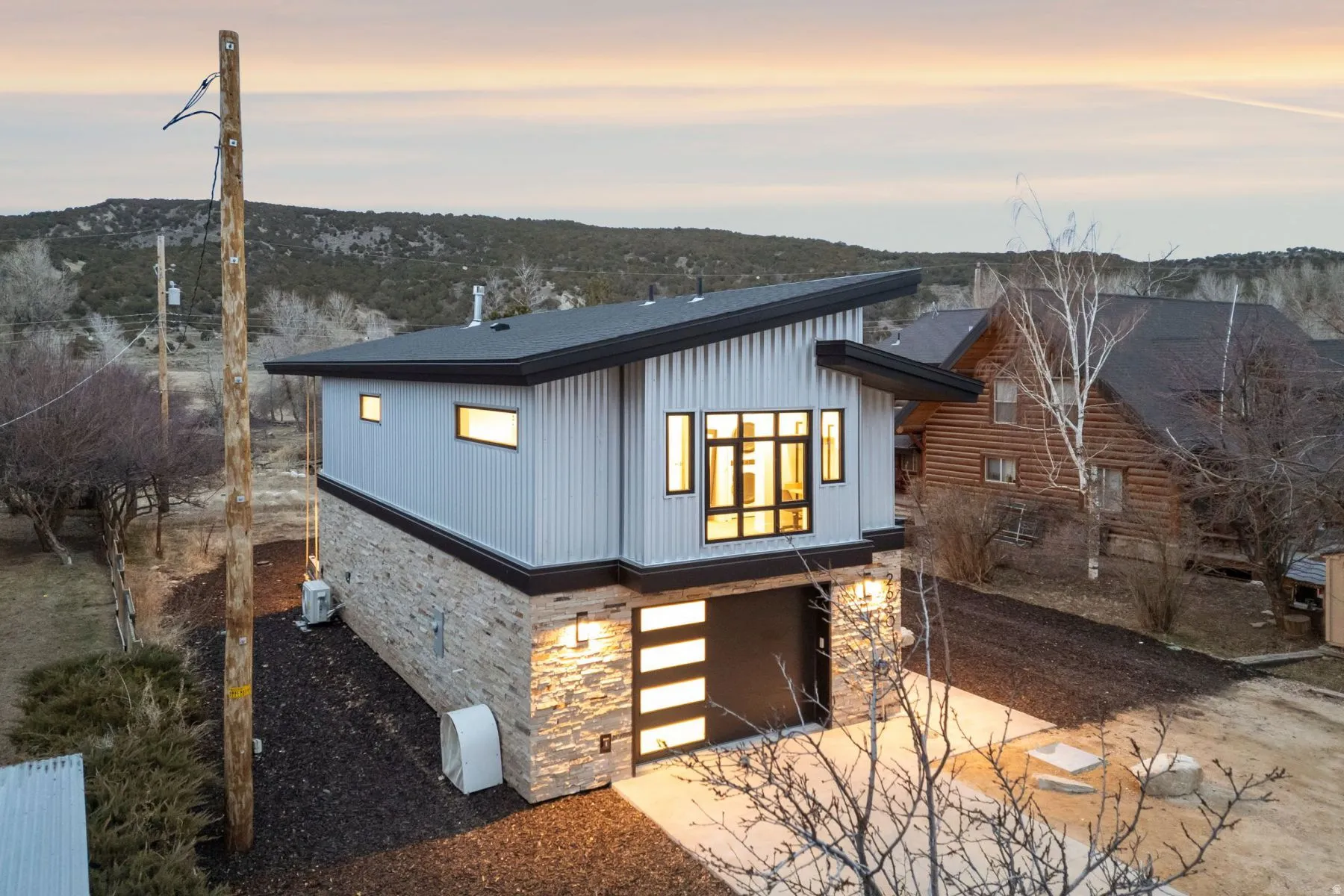 View of front facade featuring stone siding, a garage, and driveway