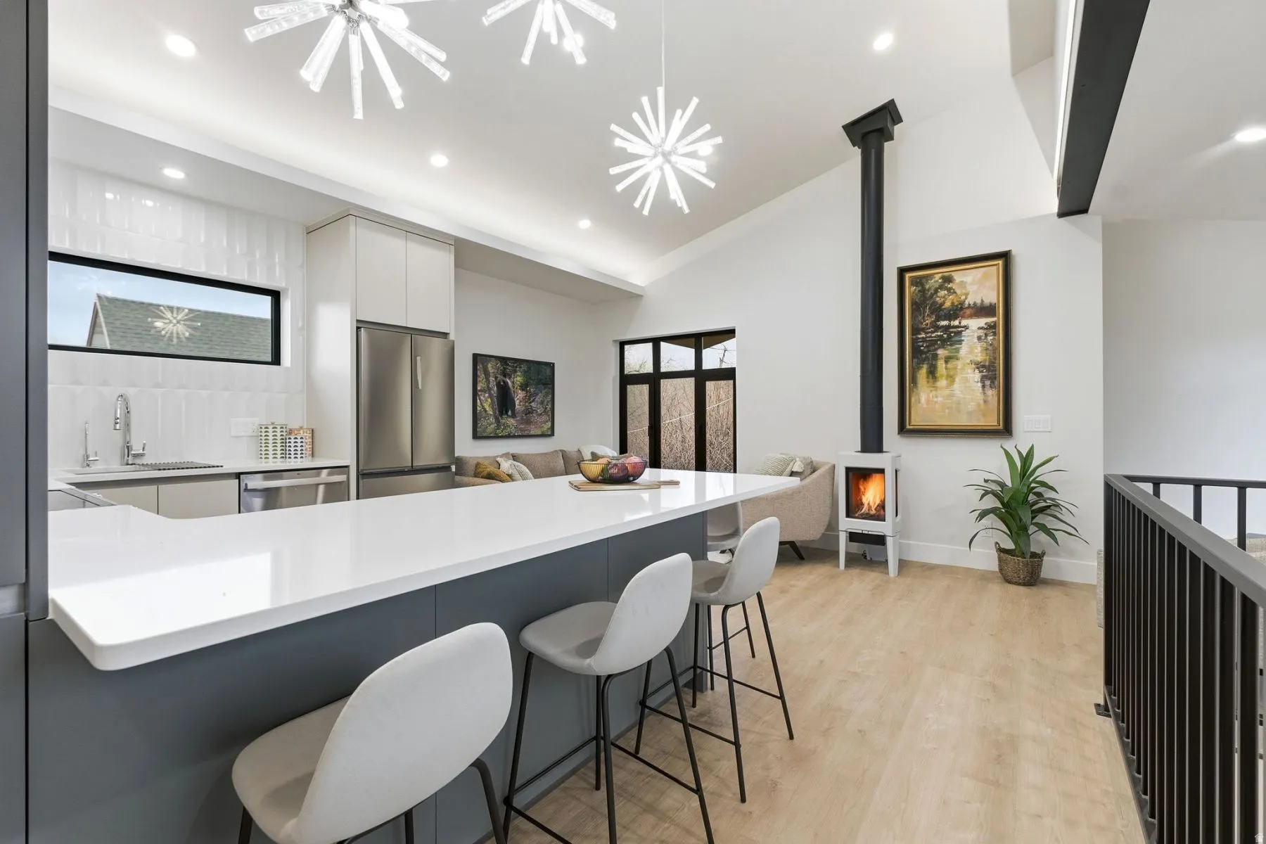 Kitchen with a wood stove, a kitchen breakfast bar, stainless steel appliances, light wood-type flooring, and modern cabinets