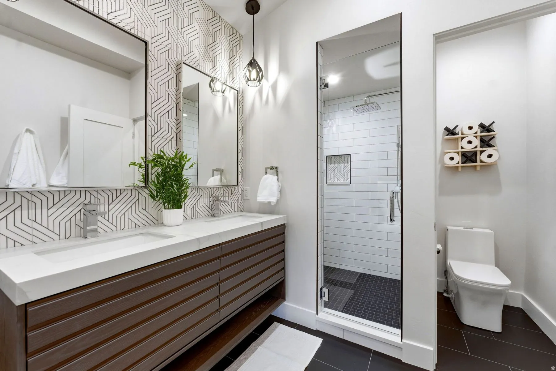 Full bathroom featuring a stall shower, double vanity, dark tile patterned flooring, and decorative backsplash