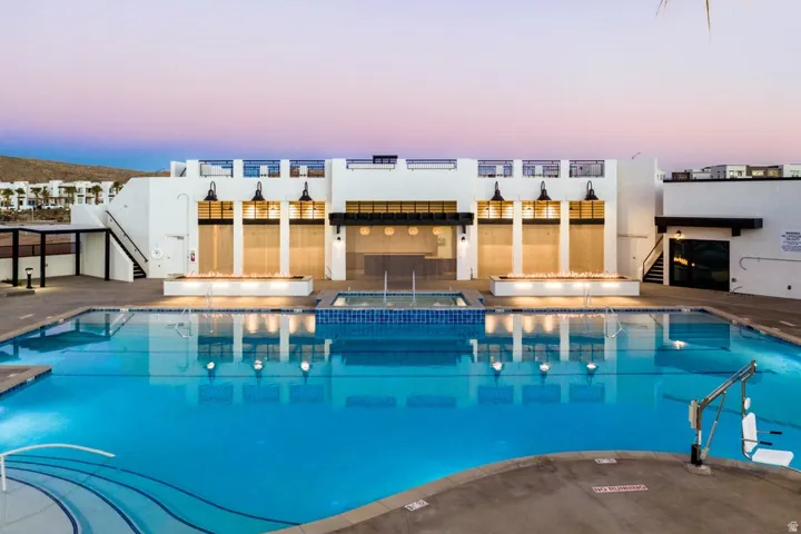 Pool at dusk featuring a community pool, a community hot tub, and a patio