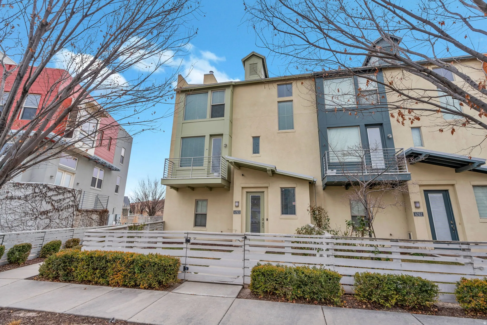 View of front of house featuring stucco siding, a fenced front yard, a gate, a chimney, and a balcony