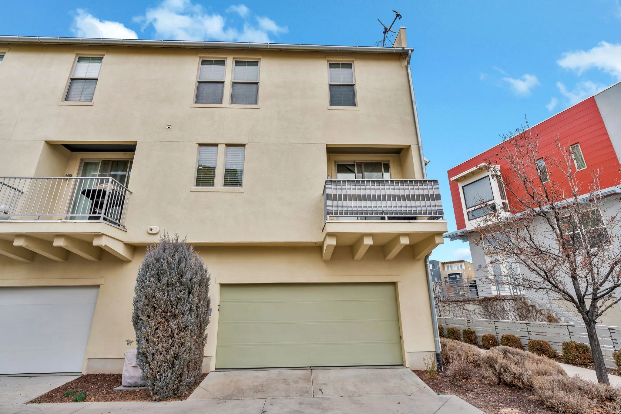 Back of property with a balcony, stucco siding, a garage, and concrete driveway