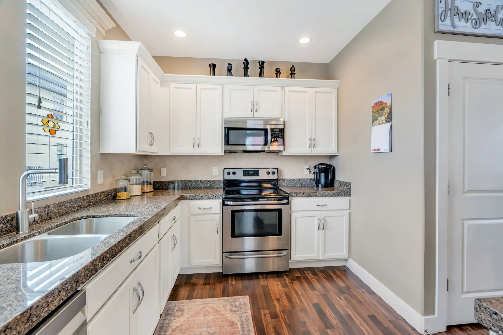 Kitchen with white cabinetry, stainless steel appliances, dark wood-style floors, and recessed lighting