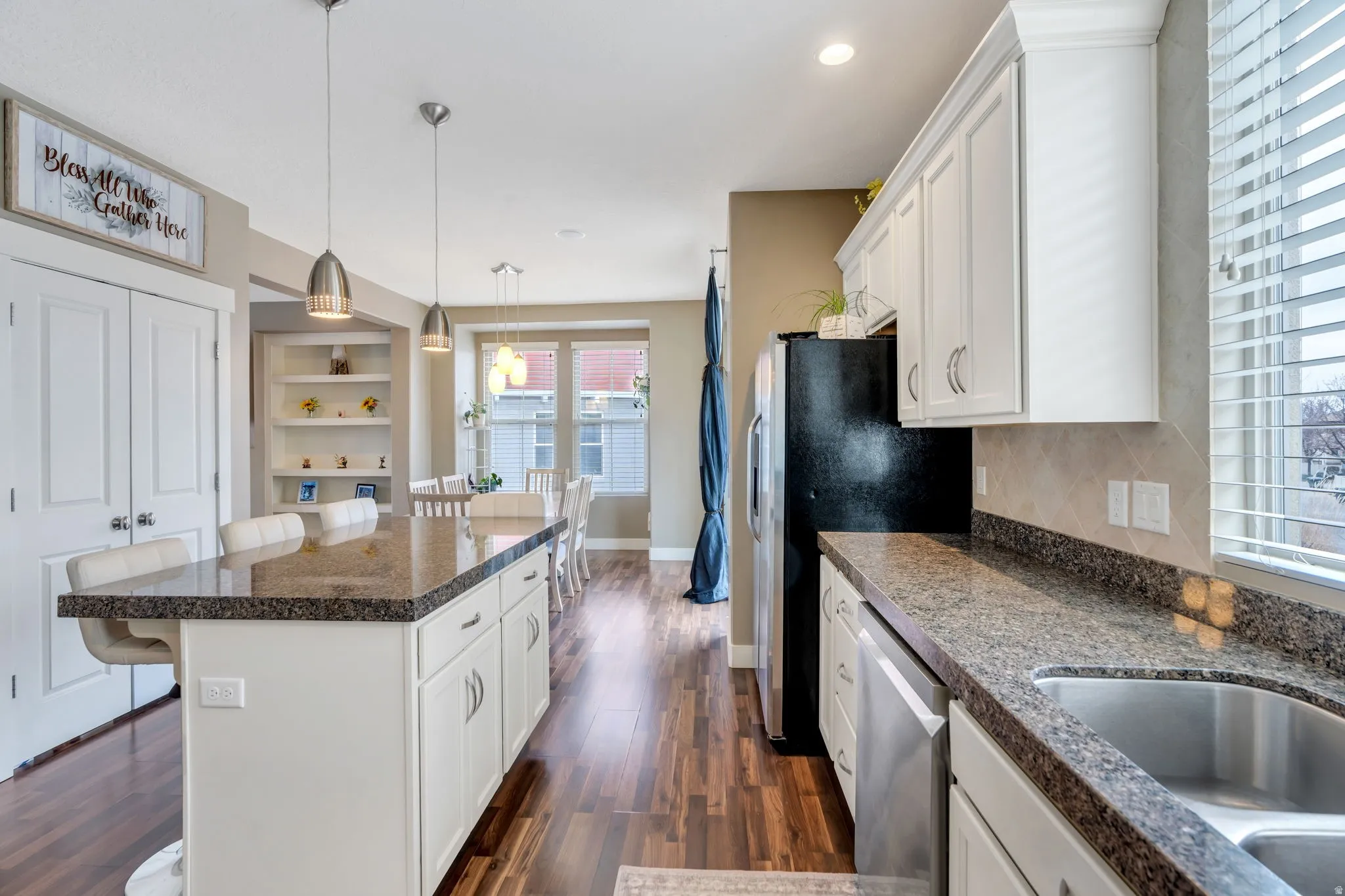 Kitchen with a kitchen bar, white cabinets, a kitchen island, pendant lighting, and dishwasher