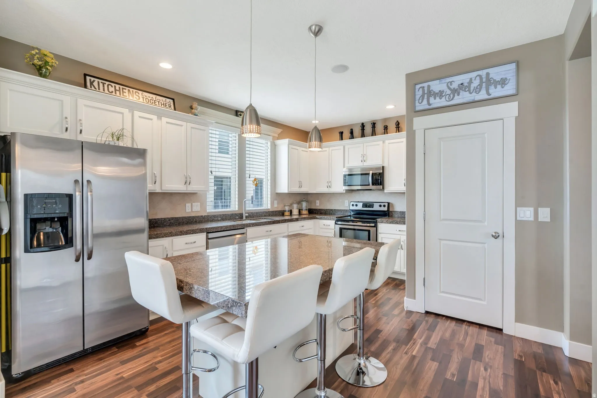 Kitchen featuring stainless steel appliances, white cabinetry, pendant lighting, a breakfast bar, and a center island