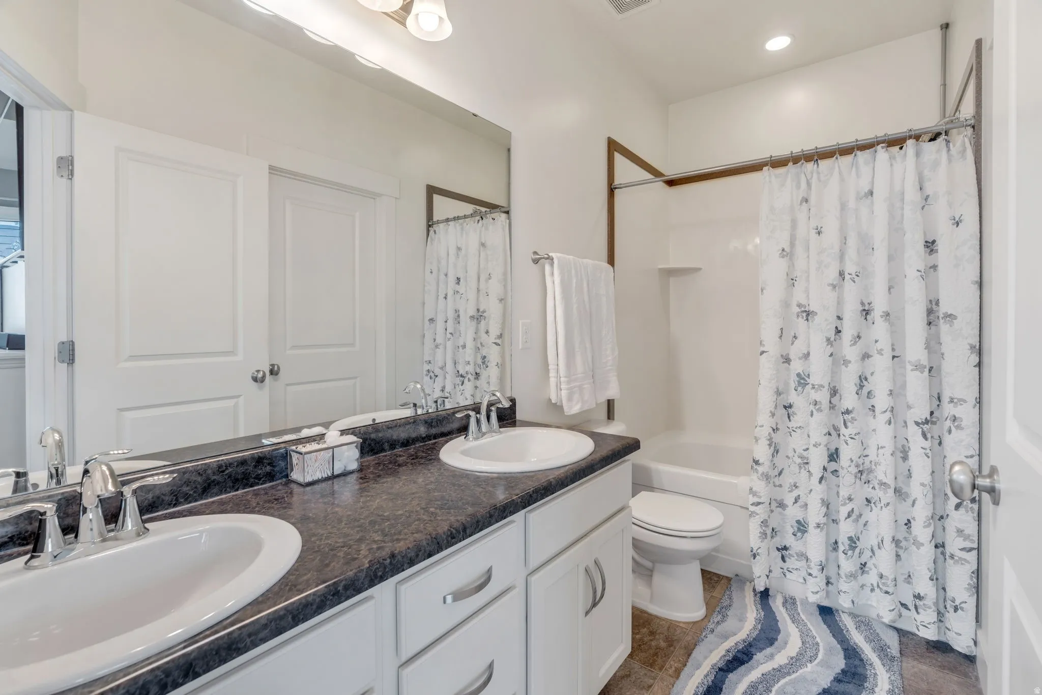 Bathroom featuring double vanity and shower / tub combo