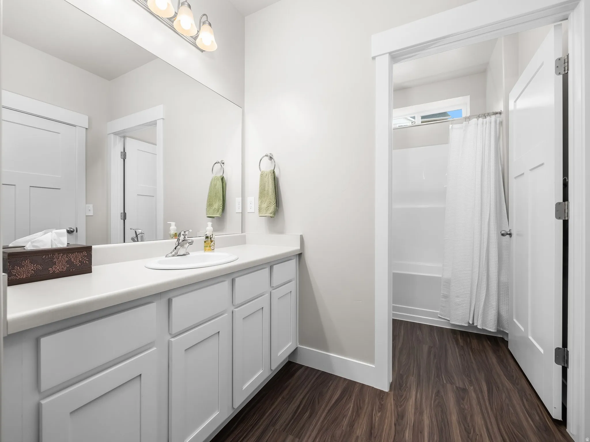 Bathroom with shower / bathtub combination with vanity, and wood-type flooring