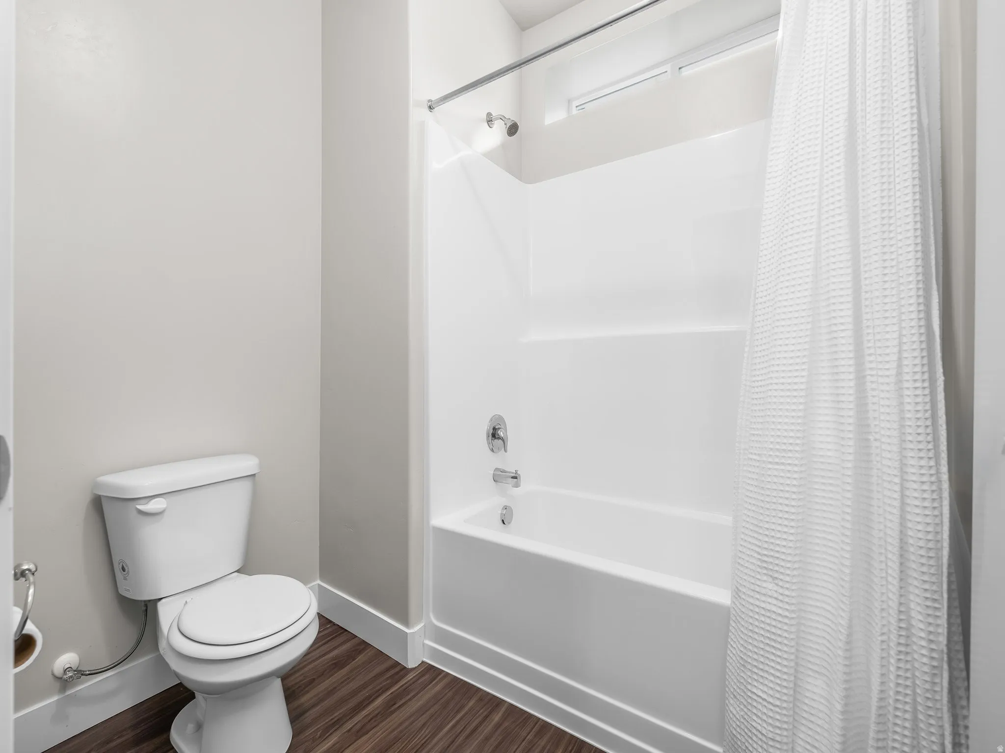 Bathroom featuring shower / tub combo with curtain and wood-style flooring
