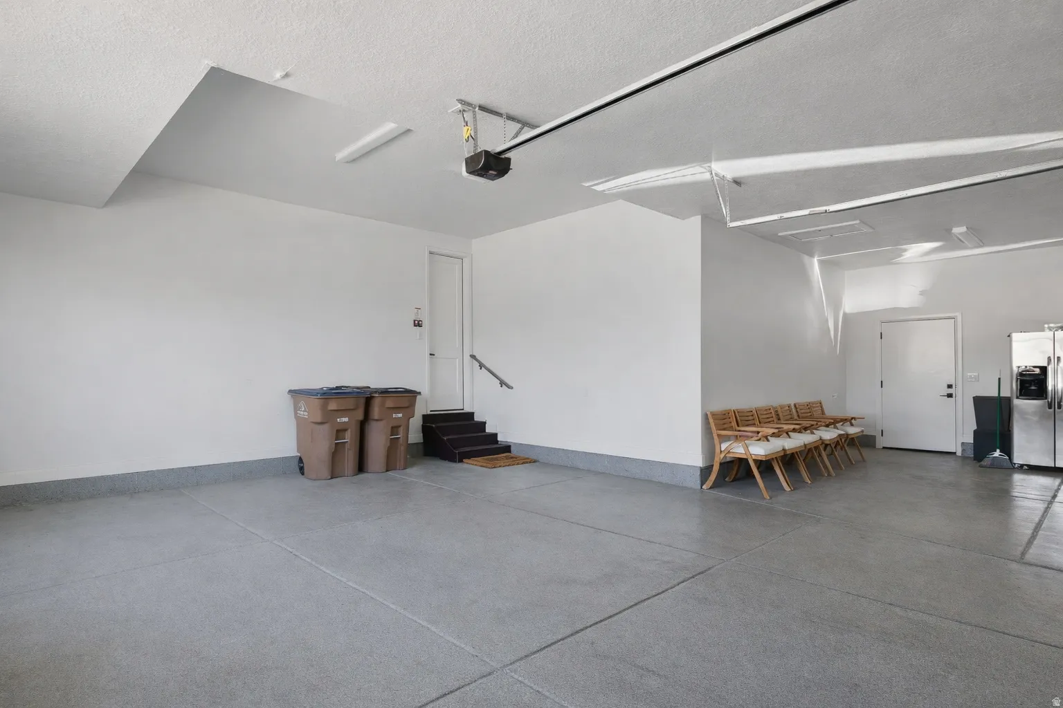 Large 3-Car Garage with ample storage space and 220 Volt charging outlet and sealed concrete floor. Entrance shown to the Mud Room and Exit to the back yard patio area. Also featuring a Radon Mitigation System.