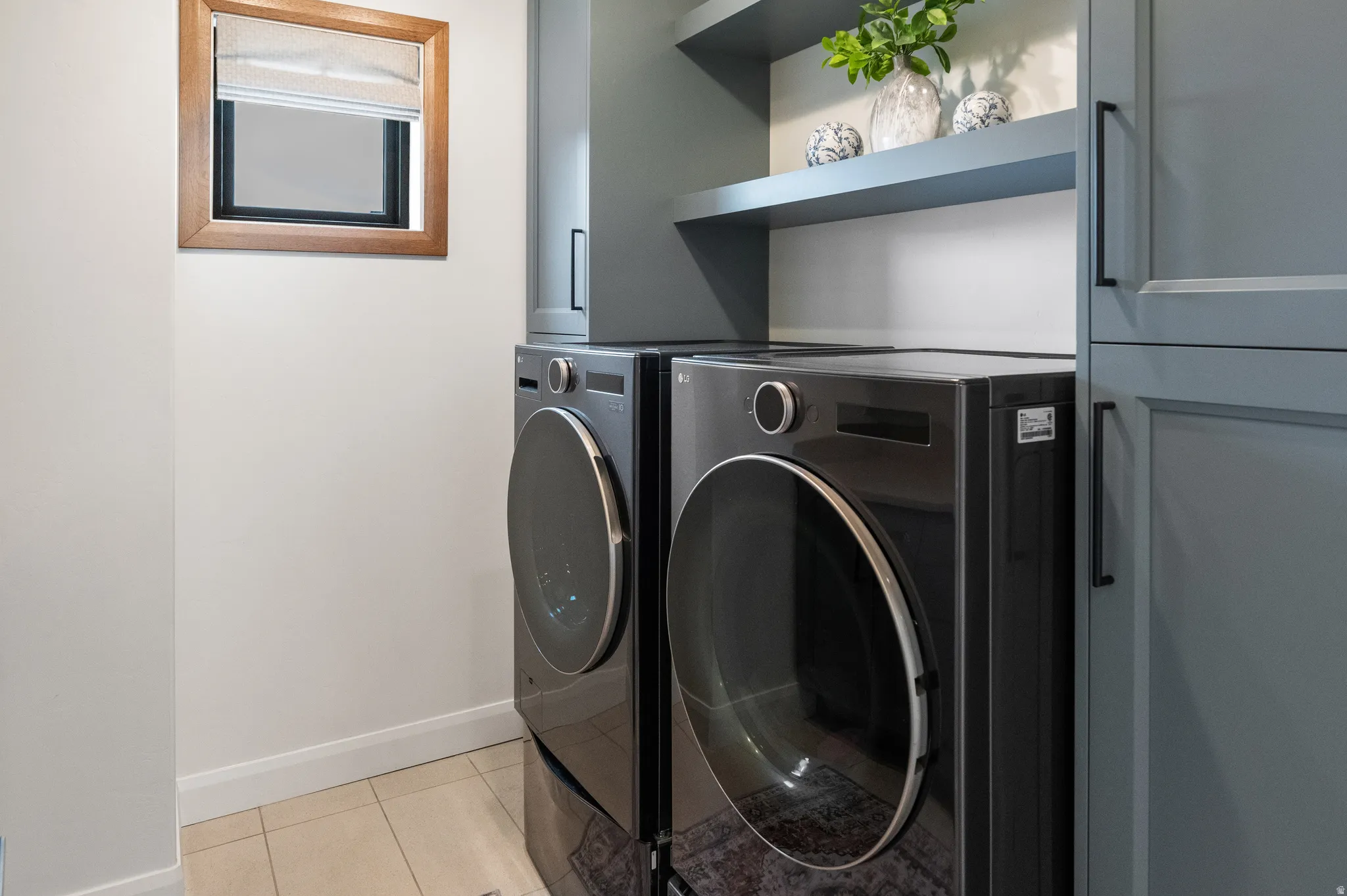 Laundry & Craft Room area featuring washing machine and clothes dryer and light tile patterned flooring and full cabinets and counter on the opposite wall.