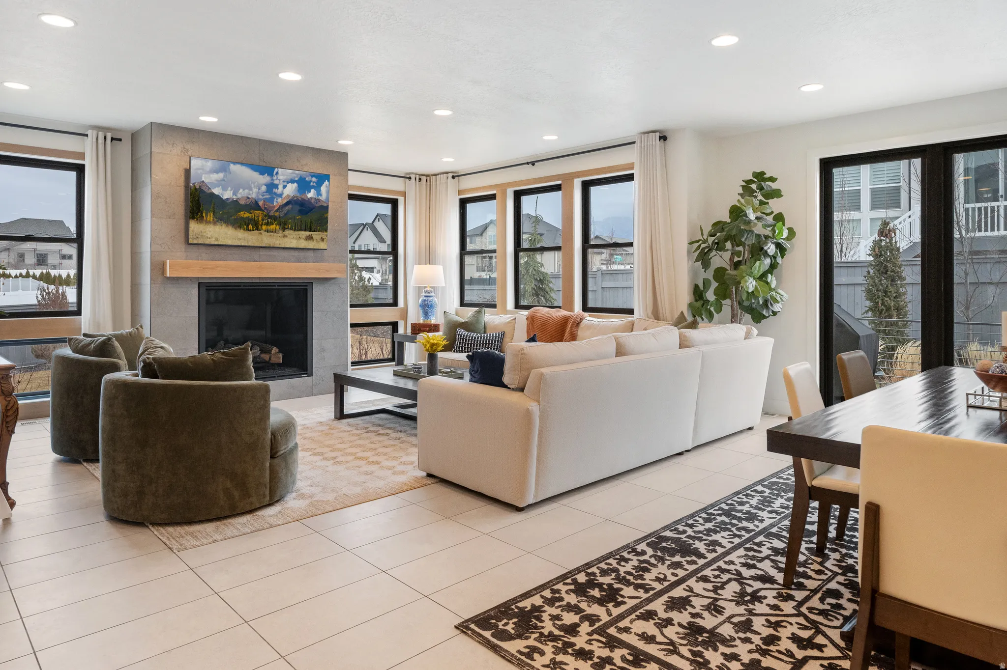 Living room with a fireplace, plenty of natural light, light tile patterned floors, and recessed lighting
