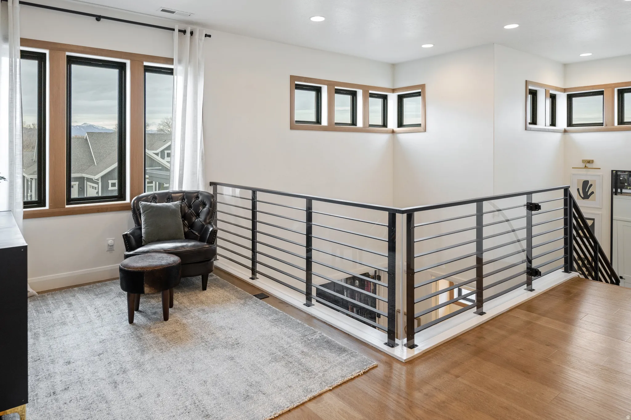 Sitting area with recessed lighting, an upstairs landing, healthy amount of natural light, and solid white oak flooring