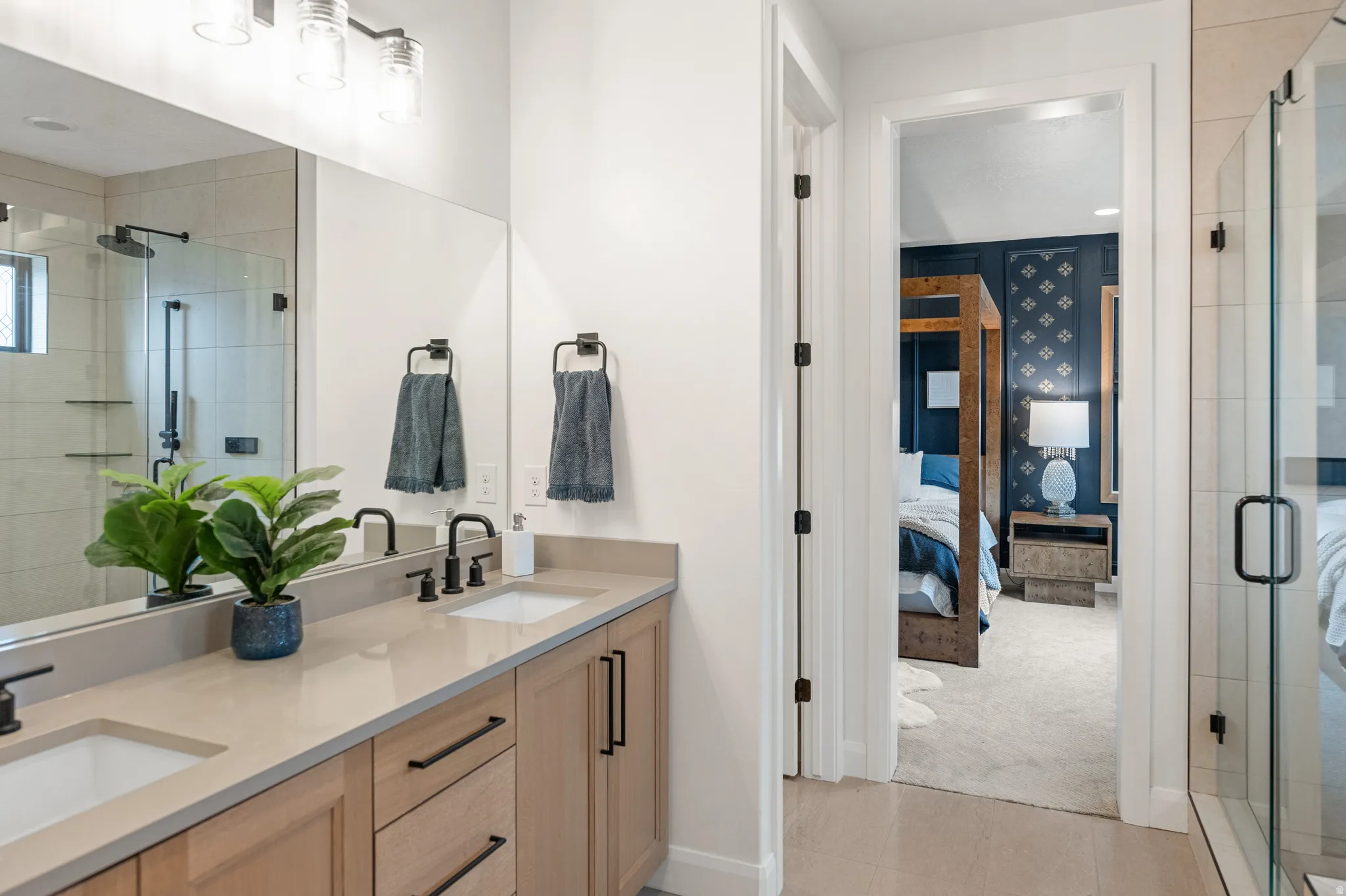 Ensuite primary bathroom featuring a large stall shower, double vanity, and light tile patterned floors