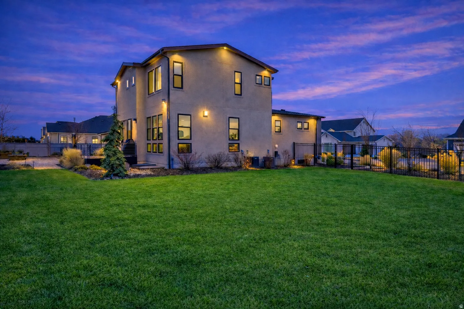 Back of house at dusk with a fenced backyard and large deck and entertaining area