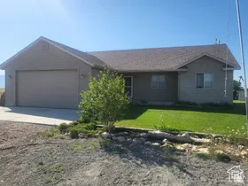 Single story home featuring driveway, a front lawn, and a garage