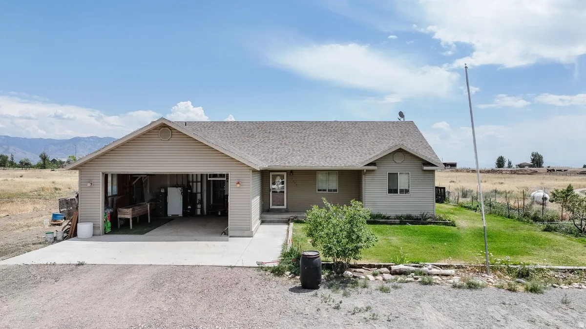 View of front of home with a front lawn, driveway, roof with shingles, and a garage