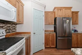 Kitchen with white appliances, dark wood-style flooring, light stone countertops, backsplash, and vaulted ceiling