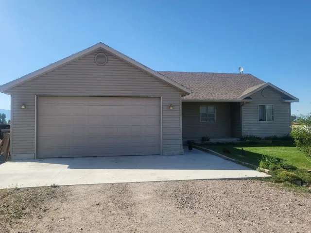 Ranch-style residence featuring light-colored siding, a two-car garage, and a concrete driveway