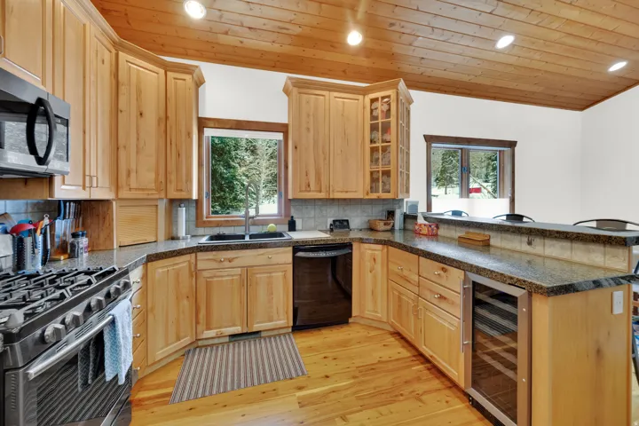 Kitchen featuring stainless steel appliances, light wood finish cabinets, wine cooler, recessed lighting, and light wood-style floors