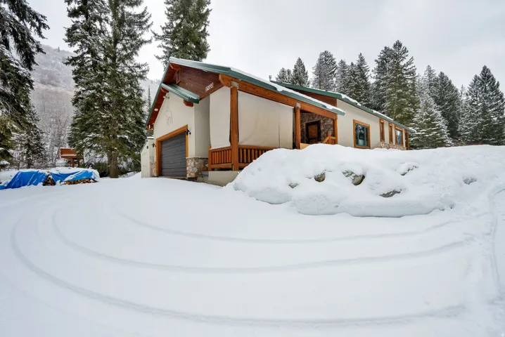 Snow covered property featuring stone siding and stucco siding