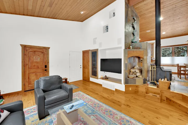 Living area with a high wood ceiling, light wood-style flooring, and a wood stove