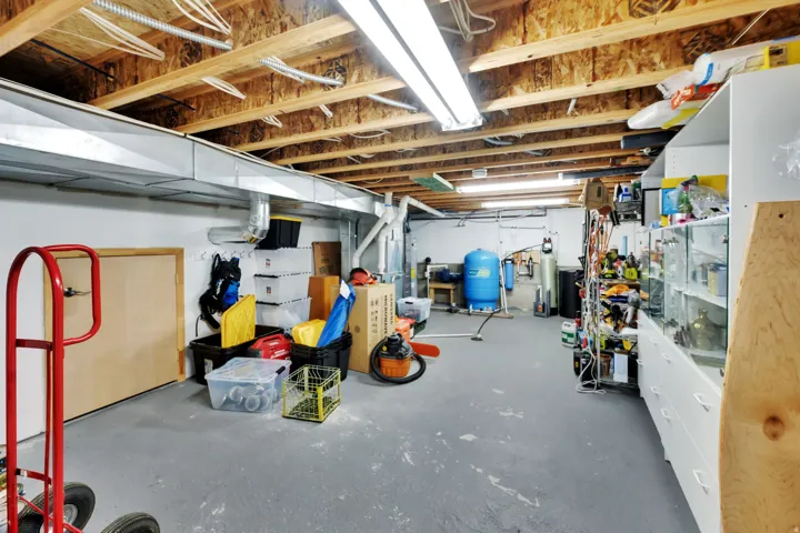 Unfinished below grade area featuring a water pressure tank and a water softener system