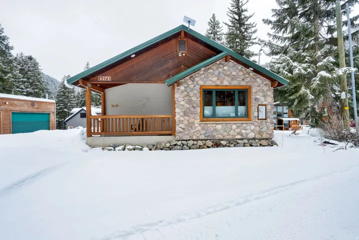 View of front of property featuring an outdoor structure, a porch, and stone siding