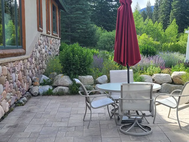 Paver patio area featuring a stone-clad exterior wall and natural rock landscaping